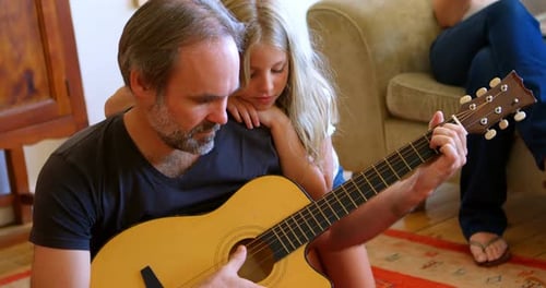 Father Playing Guitar with Daughter Leaning On Him