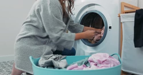 Woman Loading Clothes into Washing Machine at Home