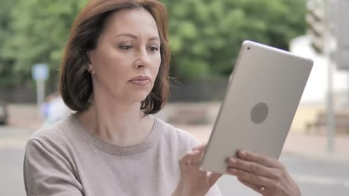 Old Woman Using Tablet Standing Outdoor on Footpath