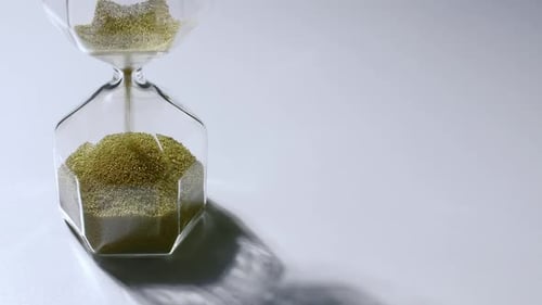 Golden Beads Flowing Through Clear Hourglass
