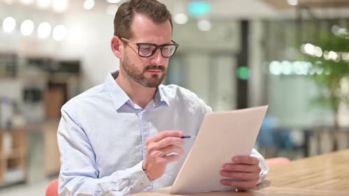 Focused Businessman Reading Documents in Office