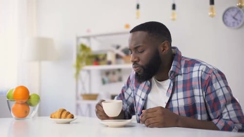 Man Experiences Heartburn While Drinking Coffee at Home