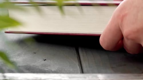 Female Hands Put Red Hard Cover Book on Wooden Table Close Up