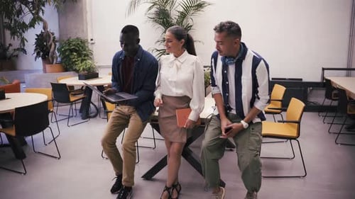 Diverse Colleagues Collaborating on Laptop in Modern Office