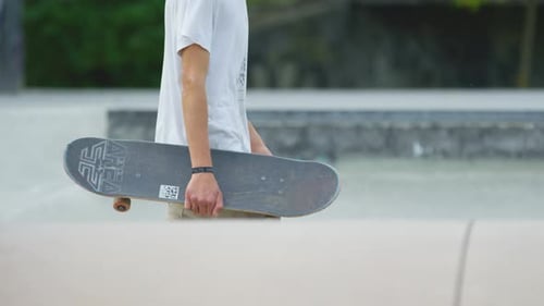 Young Adult Holding Skateboard at Skate Park