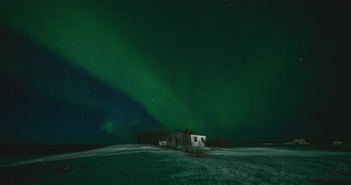 Timelapse of Aurora Borealis Northern Lights Over Small Building in the Show Field. Iceland