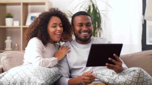 Cheerful Couple Relaxing at Home Using Tablet