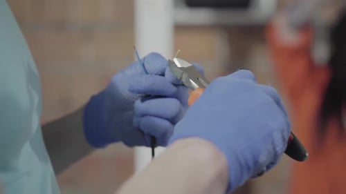 Gloved Hands Stripping Electrical Wires with Pliers