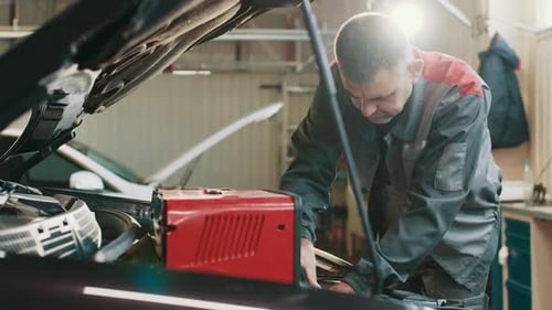 Man Servicing Vehicle Engine in Garage