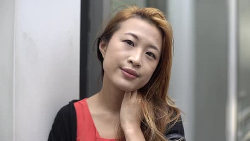 Smiling Woman Leaning Against Wall in an Urban Setting