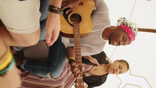 Young Adults Gather and Play Guitar Indoors