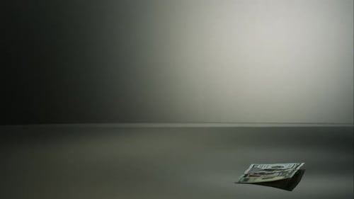 American $100 Bills Falling onto a Reflective Surface