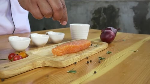 chef or cook seasoning fresh chunk of deli piece of beef with sea salt and grounded spicy peppers.