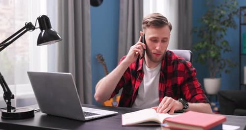Man working from home on laptop talking on phone