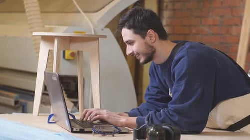 Woodworker Using Laptop in Workshop