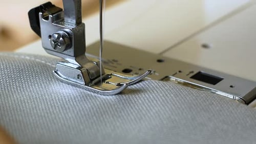 Woman hands with gray fabric sewing with a sewing machine. Women's hands sew on a sewing machine.