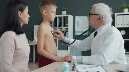 Doctor Examining Child with Stethoscope Then Talking To Mother in Hospital Office
