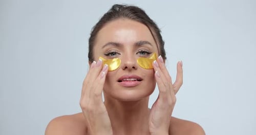 Woman with Gold Eye Patches Touches Face