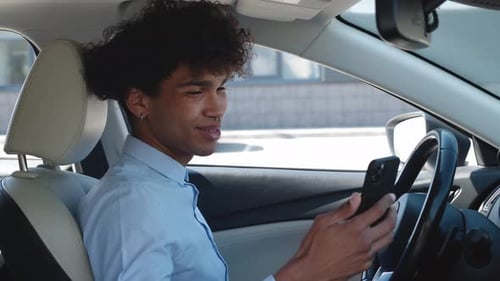 Young Adult Smiles at Phone in Car