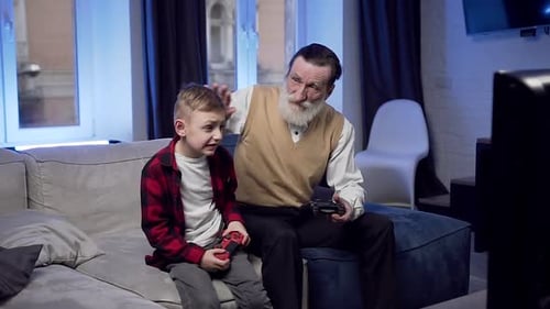 Grandson and Grandfather Play Video Games Together Indoors