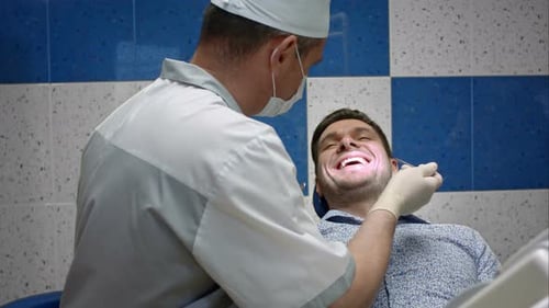 Male Dentist Examining Teeth of His Male Client