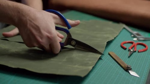 Hands Cutting Olive Textile with Scissors