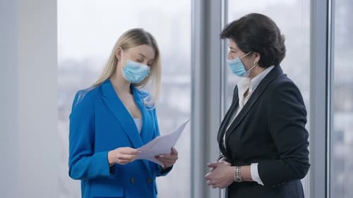 Businesswomen Discussing Documents Wearing Surgical Masks
