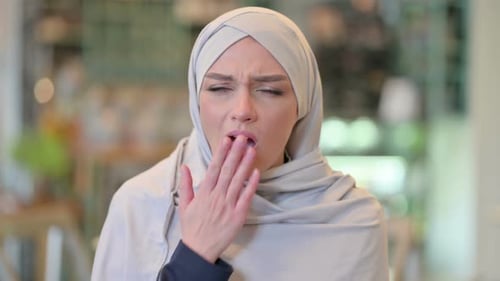 Woman in Headscarf Covers Mouth While Yawning