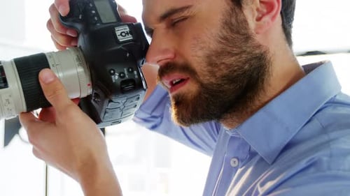 Bearded Man Looking Through DSLR Camera in Studio
