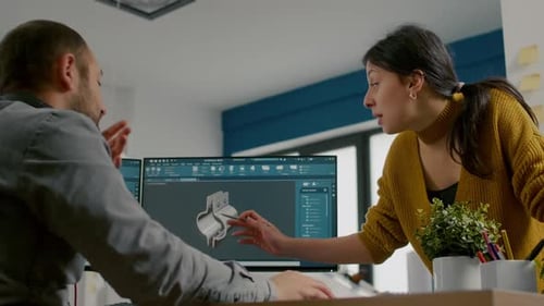 Un designer industriel discute avec un collègue tout en travaillant dans un programme de CAO
