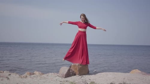 Woman in Red Dress Dances by the Sea