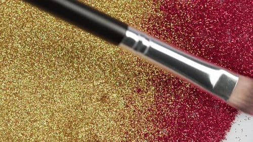 Verschmieren von rotem und goldenem Glitzer auf weißem Hintergrund Glanzpuder-Nahaufnahme