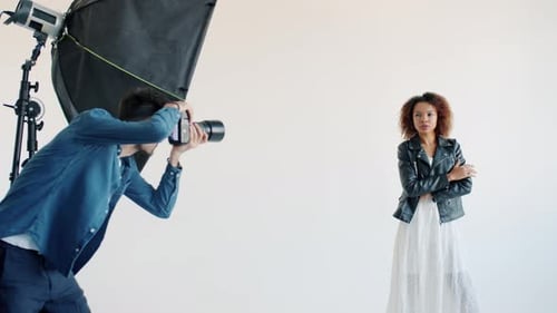 Mixed Race Model Posing for Camera in Studio and Photographer Taking Photos with Camera