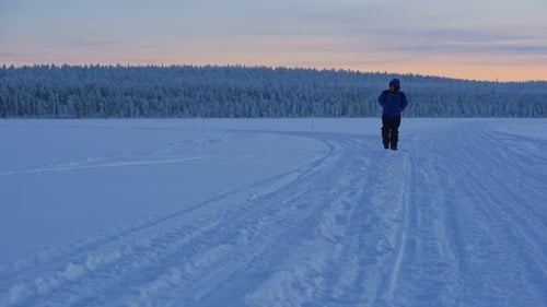 A Man In Winter Clothes Swiftly Walking In Snow And A Snow-Covered Forest In Lapland Region. -wide s