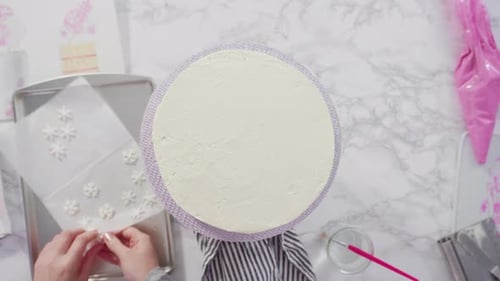 Flat lay. Step by step. Decorating round funfetti cake with pink and white fondant snowflakes
