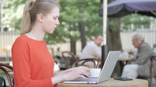Woman Working on Laptop at Outdoor Cafe