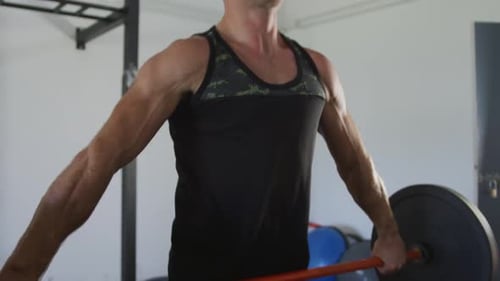 Hombre caucásico en forma entrenando, haciendo ejercicio, levantando pesas dentro del gimnasio
