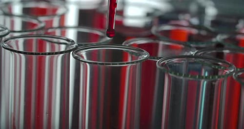 Red liquid drips into lab test tube