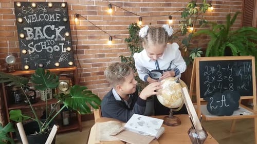 Boy and Girl Studying Globe with Magnifying Glass