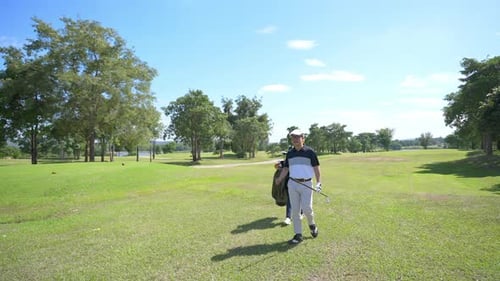 4K Asian man golfer walking on golf course together with female caddy