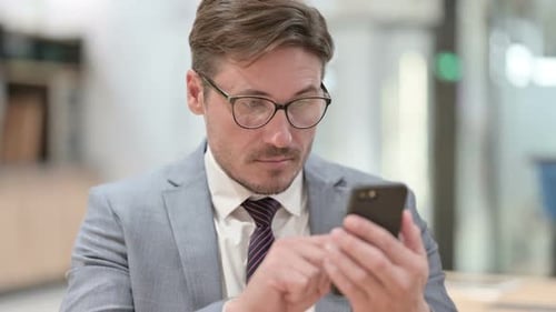 Man in Suit Using Smartphone in Office