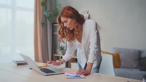 Young Female Entrepreneur Using Laptop Writing Notes Stand at Home Office Desk