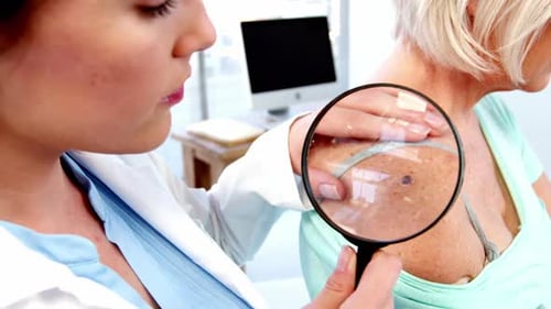 Doctor Examines Mole on Patient with Magnifying Glass