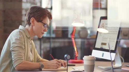 Businesswoman Working on Computer and Taking Notes in Office