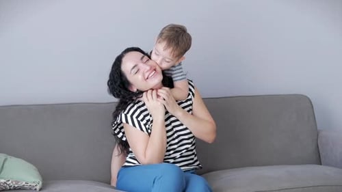 Smiling Woman Embraced by Child on Couch