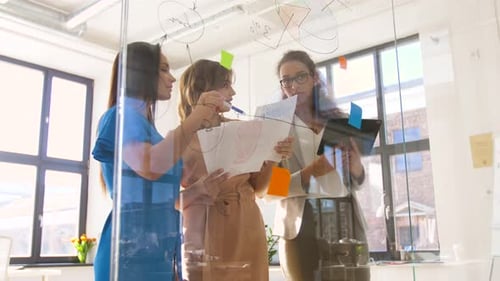 Businesswomen with Pie Chart on Office Glass Board