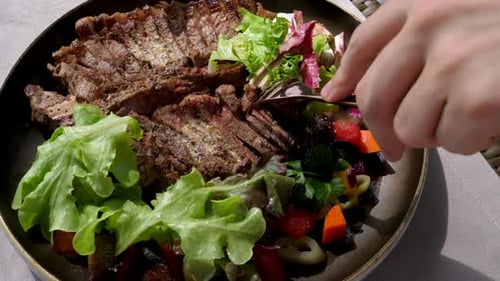 Man Hand with Fork Take Portion of Fresh Roasted Beef Steak in Restaurant