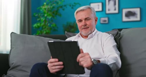 Adult Man Relaxing with Tablet on Couch