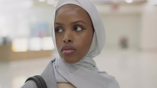 Nachdenkliche schwarze Dame mit Hijab auf dem Kopf im Einkaufszentrum