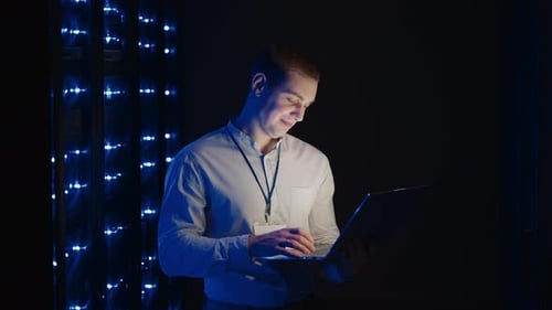 Man Working on Laptop in a Server Room